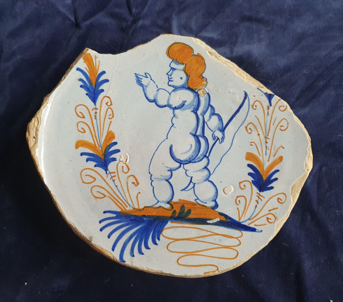 A rare, large shard from a plate, featuring a depiction on the base of a striding putto with a bow . 17th