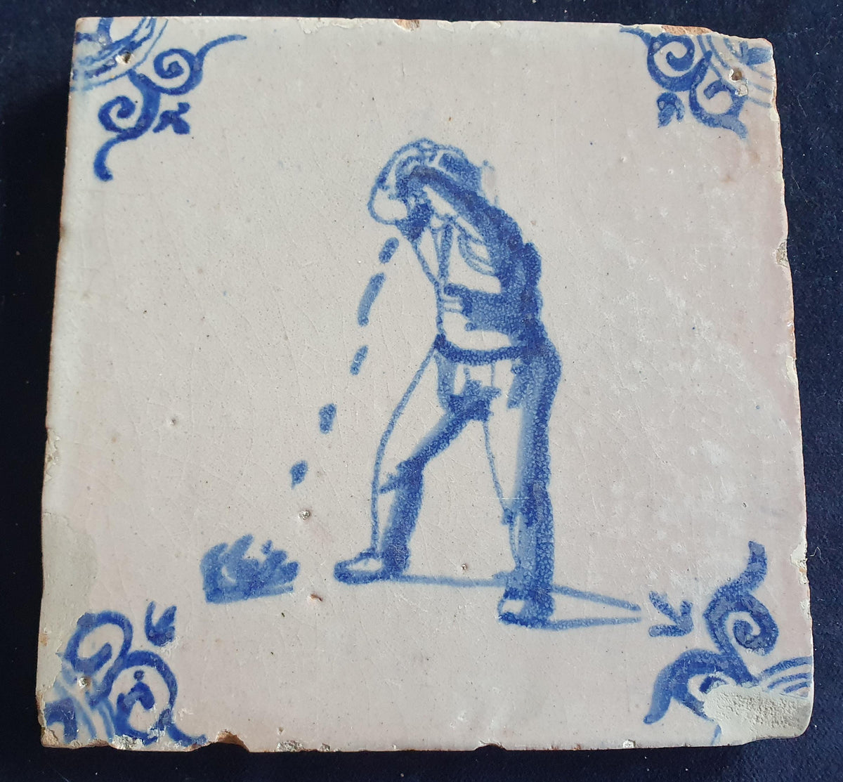 Antique Delft tile, dating from around 1650, depicts a man spitting. Figuretile