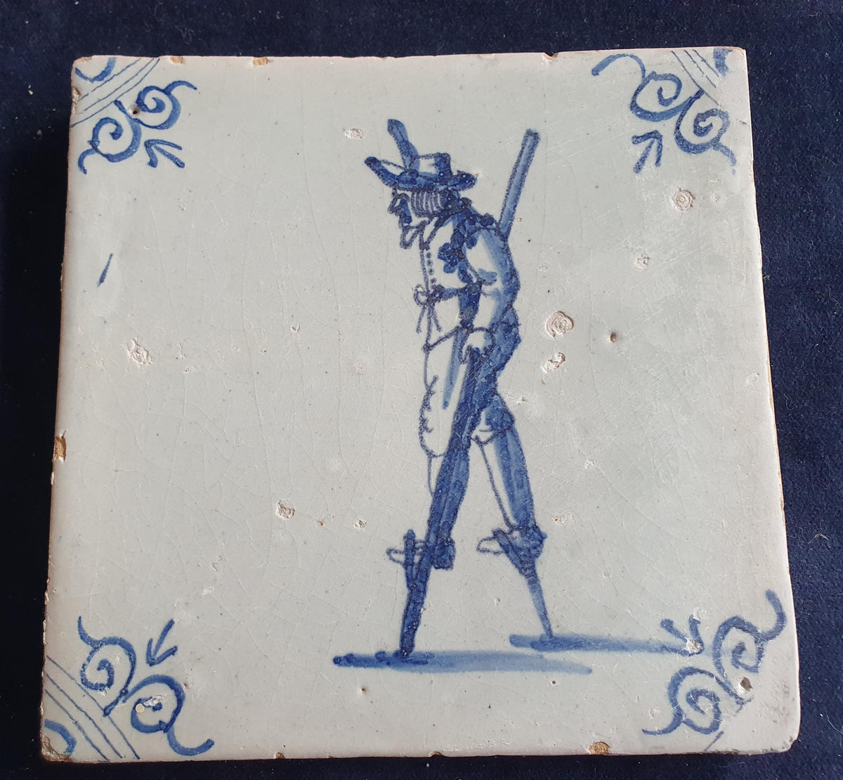 Antique Delft tile depicting a children's activity: walking on stilts.  Figuretile