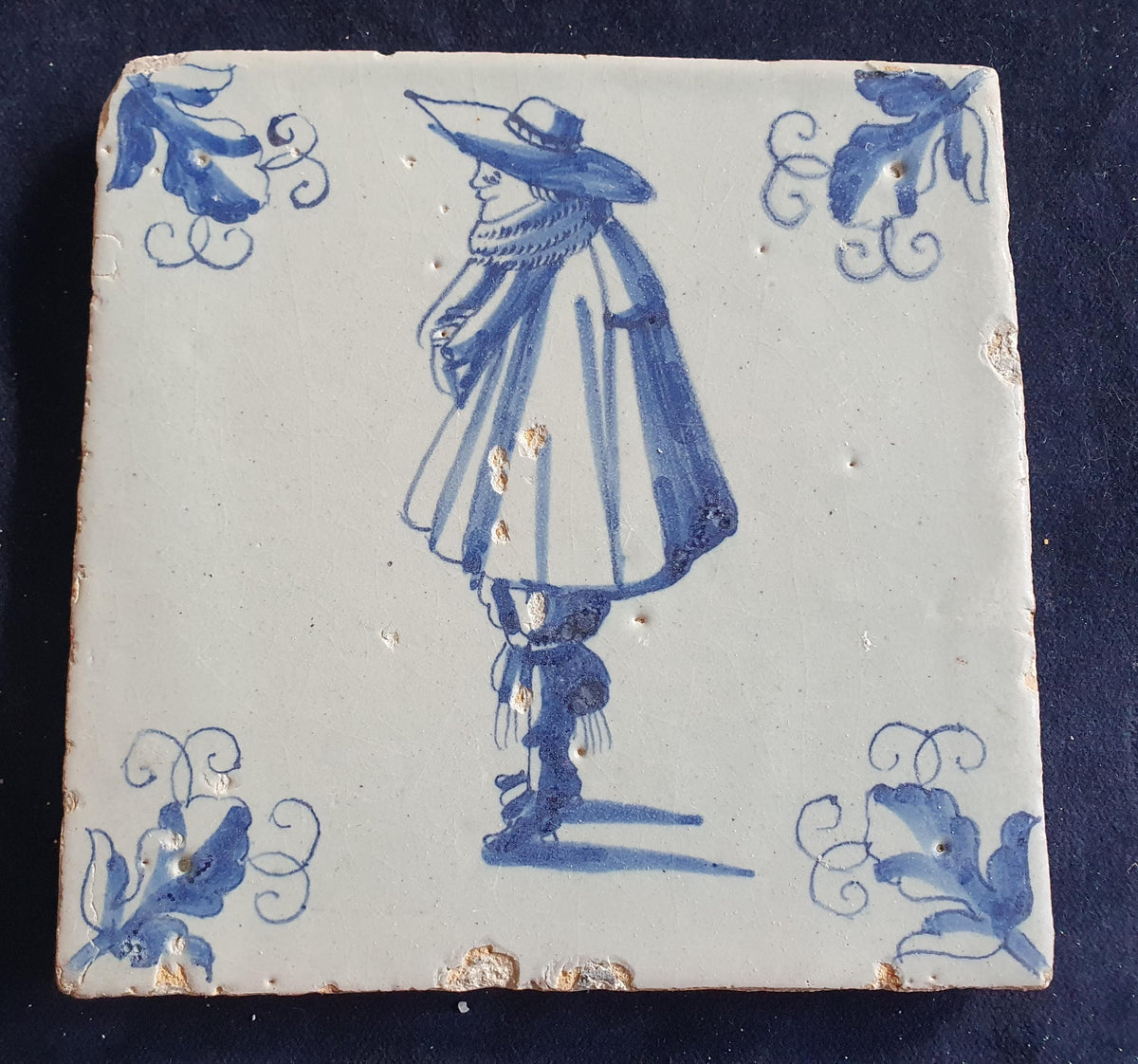 Antique Delft tile depicts a stylishly dressed gentleman in blue; he is wearing a large hat. Figuretile