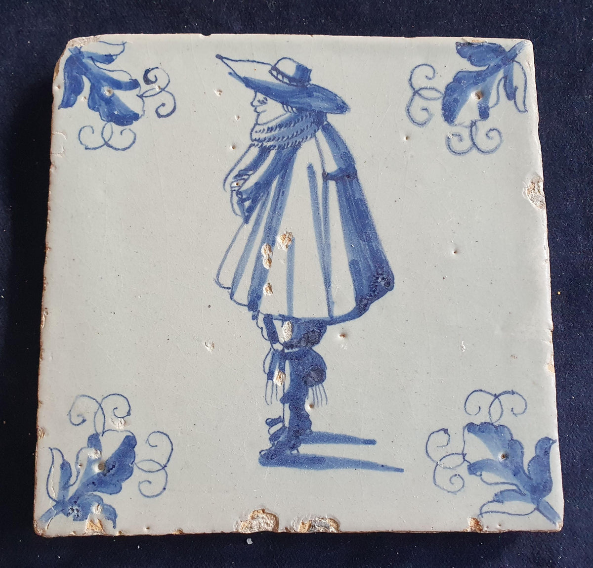 Antique Delft tile depicts a stylishly dressed gentleman in blue; he is wearing a large hat. Figuretile