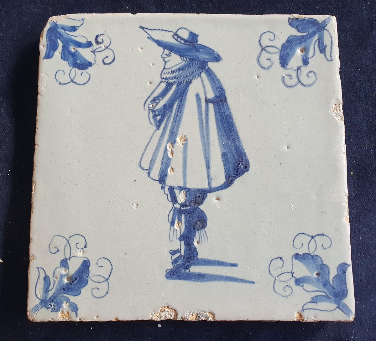 Antique Delft tile depicts a stylishly dressed gentleman in blue; he is wearing a large hat. Figuretile