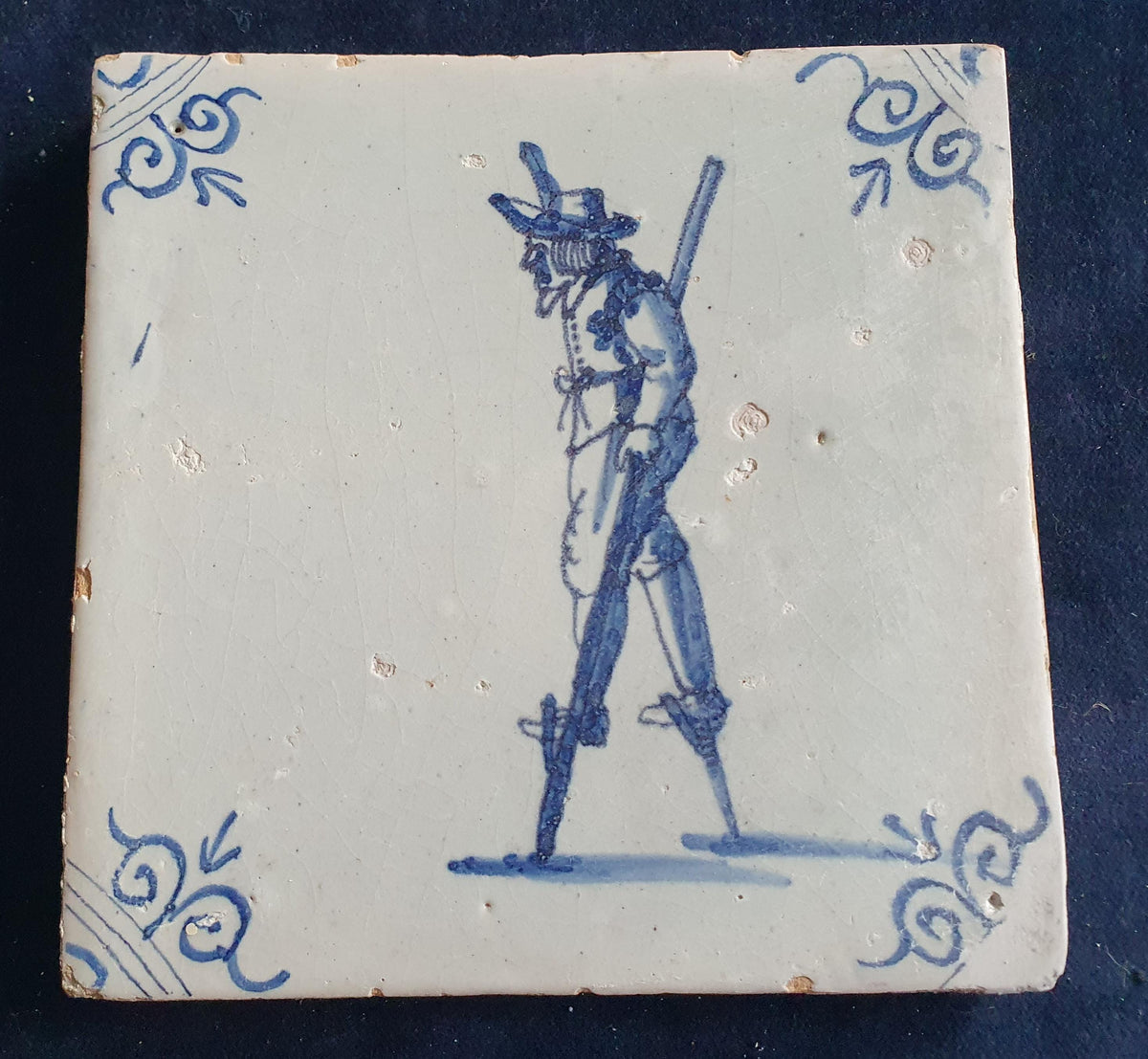 Antique Delft tile depicting a children's activity: walking on stilts.  Figuretile