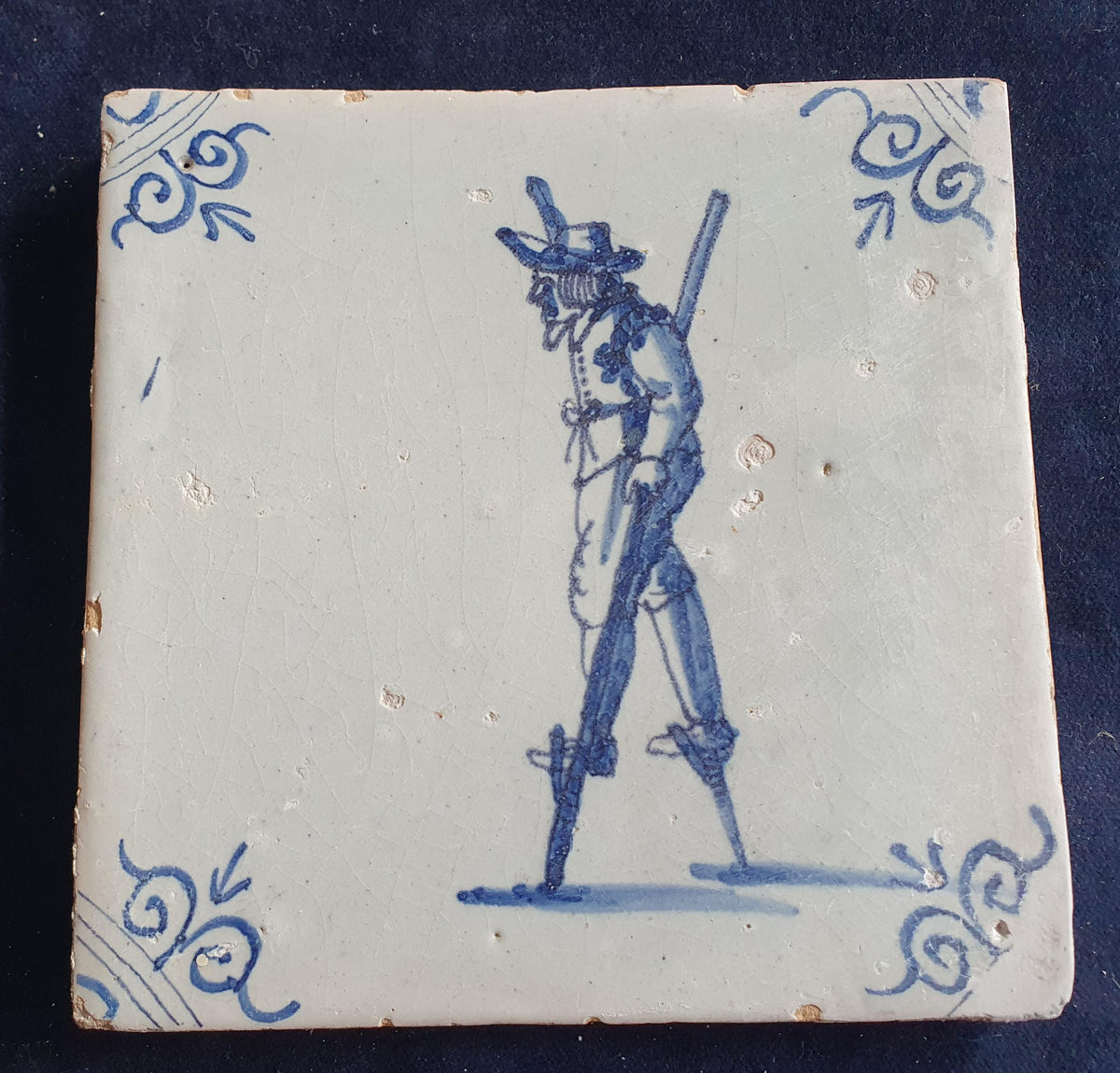 Antique Delft tile depicting a children's activity: walking on stilts.  Figuretile