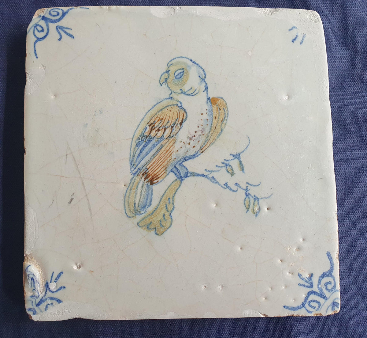 17th-century Delft tile, produced around 1640, featuring a beautifully painted parrot perched on a branch.  Animaltile
