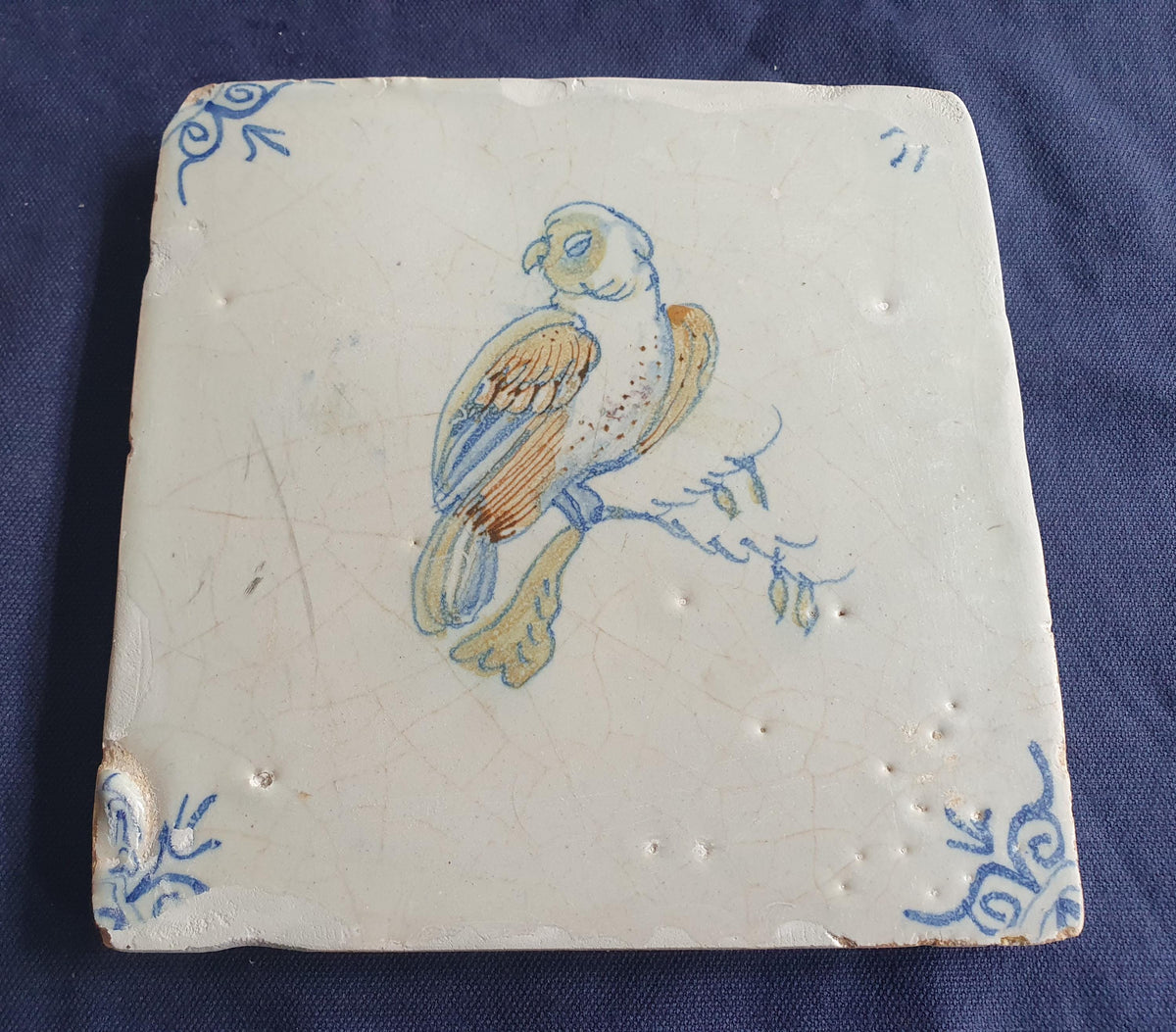 17th-century Delft tile, produced around 1640, featuring a beautifully painted parrot perched on a branch.  Animaltile