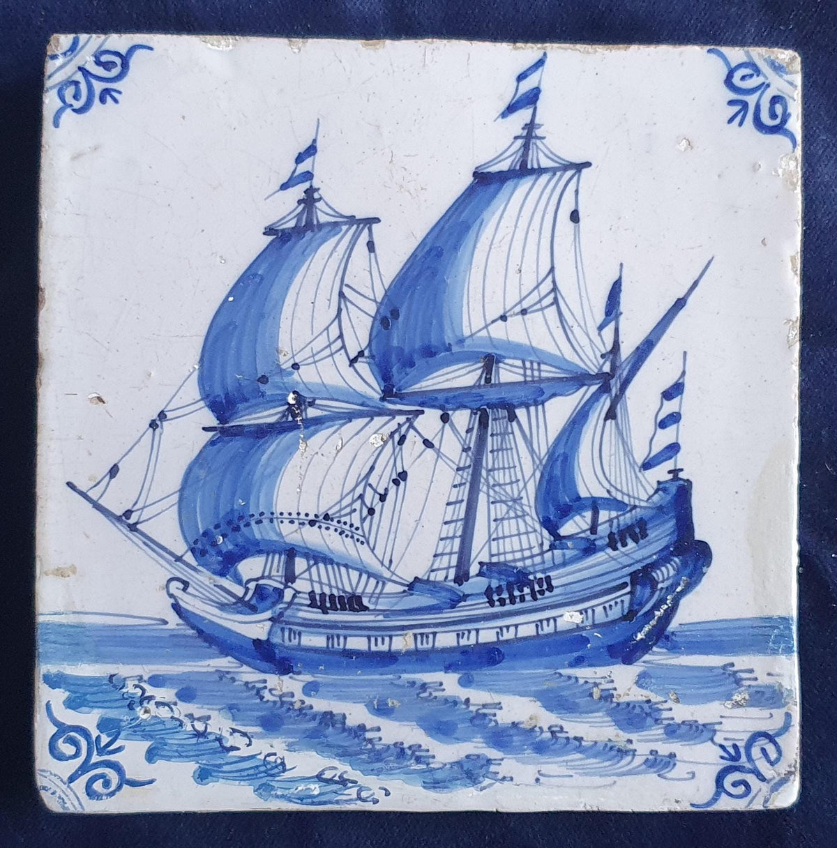 Antique Delft tile dating from around 1650, featuring a beautifully painted depiction of a fully rigged warship at sea. Shiptile