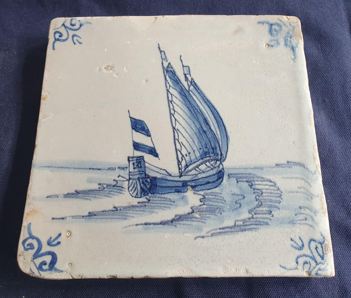 Delft tile, dating from circa 1660, is painted in blue and depicts a ship sailing. Shiptile