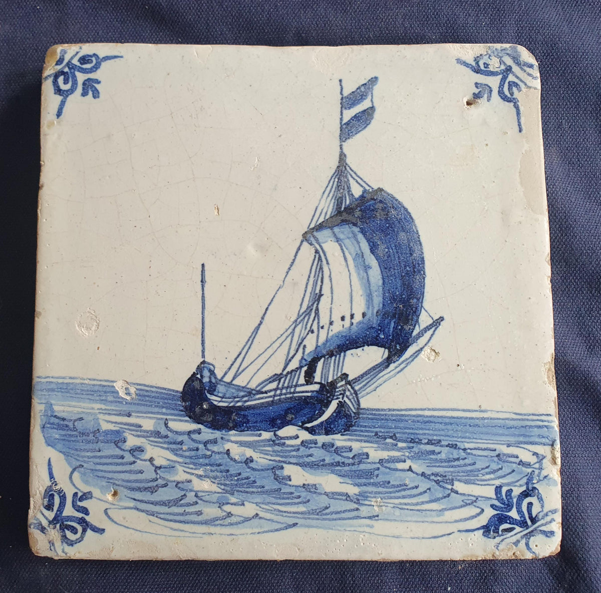 Delft tile, dating from circa 1660, is painted in blue and depicts a ship sailing. Shiptile