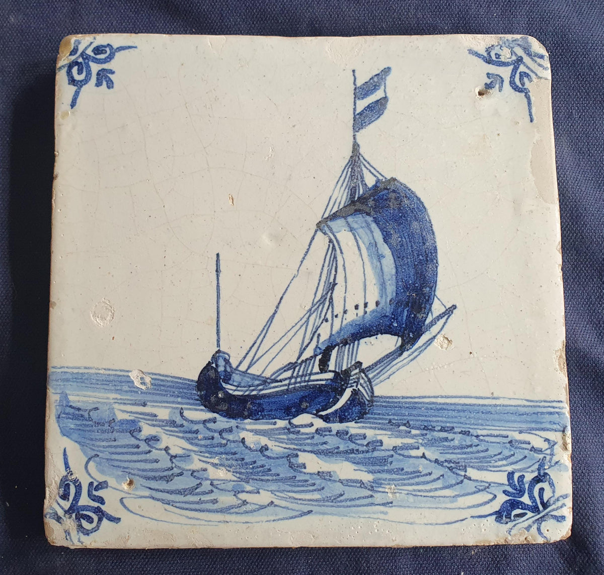 Delft tile, dating from circa 1660, is painted in blue and depicts a ship sailing. Shiptile
