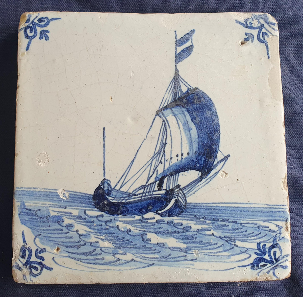 Delft tile, dating from circa 1660, is painted in blue and depicts a ship sailing. Shiptile