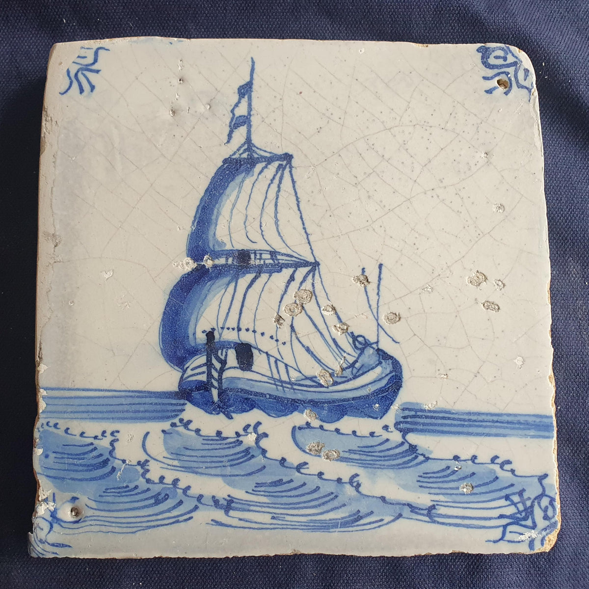 Delft tile, dating from circa 1660, is painted in blue and depicts a ship sailing. Shiptile
