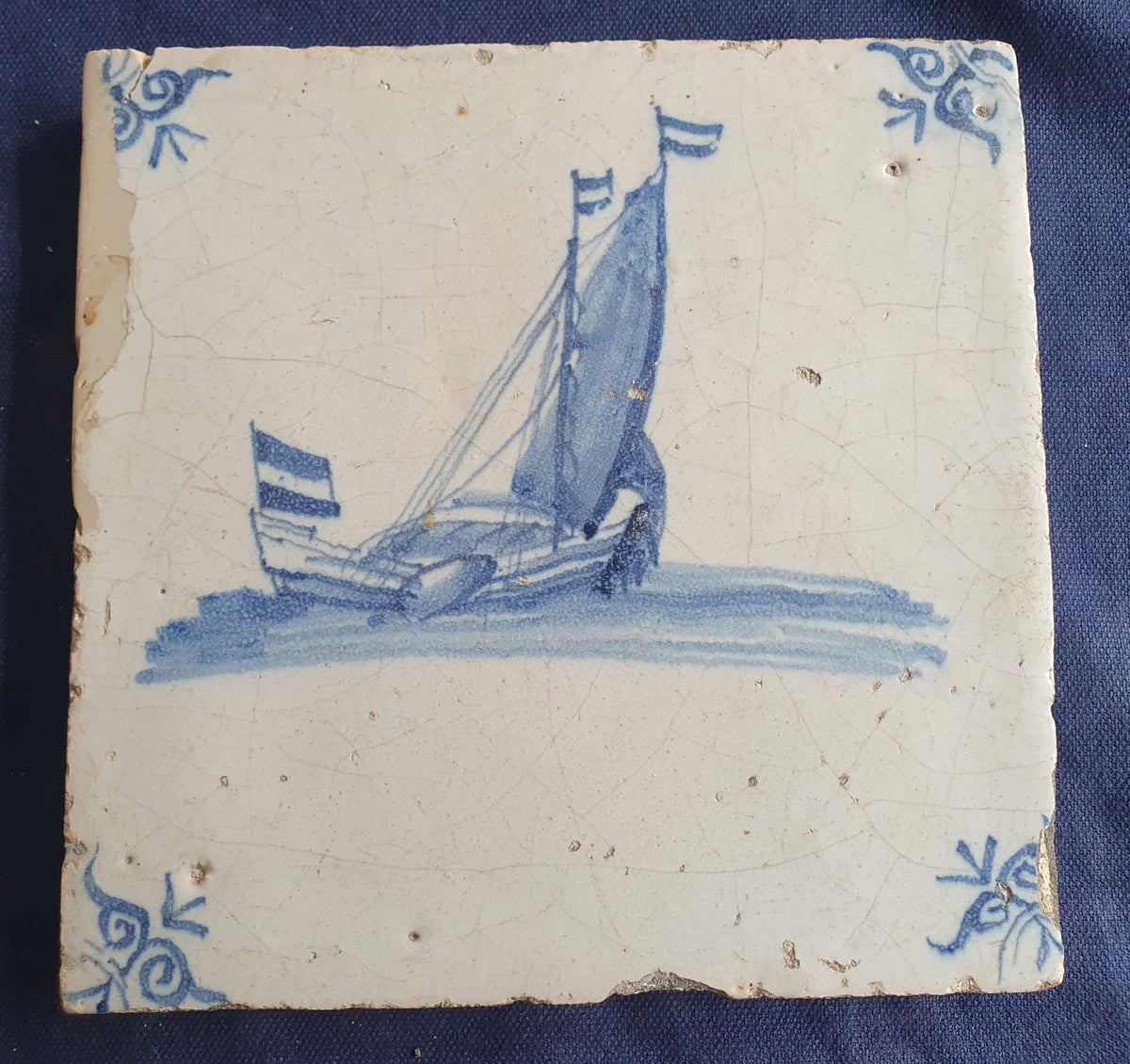 Delft tile, dating from circa 1660, is painted in blue and depicts a ship sailing. Shiptile
