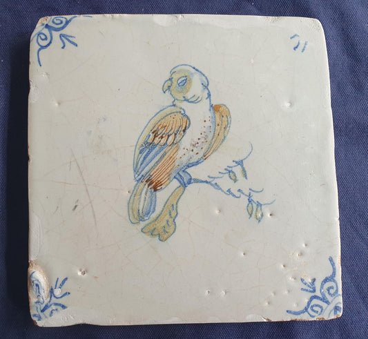 17th-century Delft tile, produced around 1640, featuring a beautifully painted parrot perched on a branch.  Animaltile