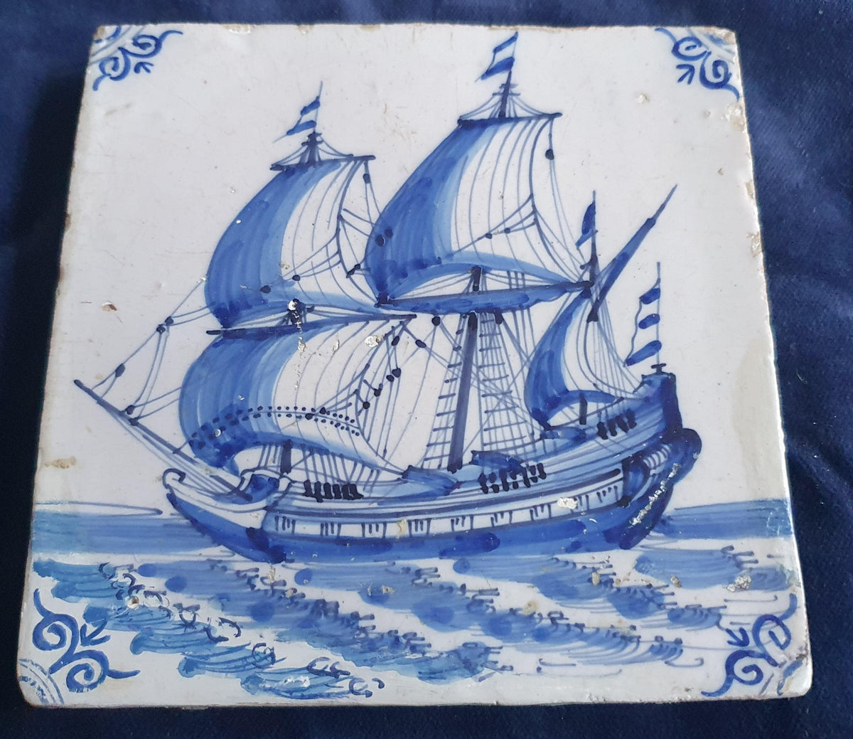 Antique Delft tile dating from around 1650, featuring a beautifully painted depiction of a fully rigged warship at sea. Shiptile