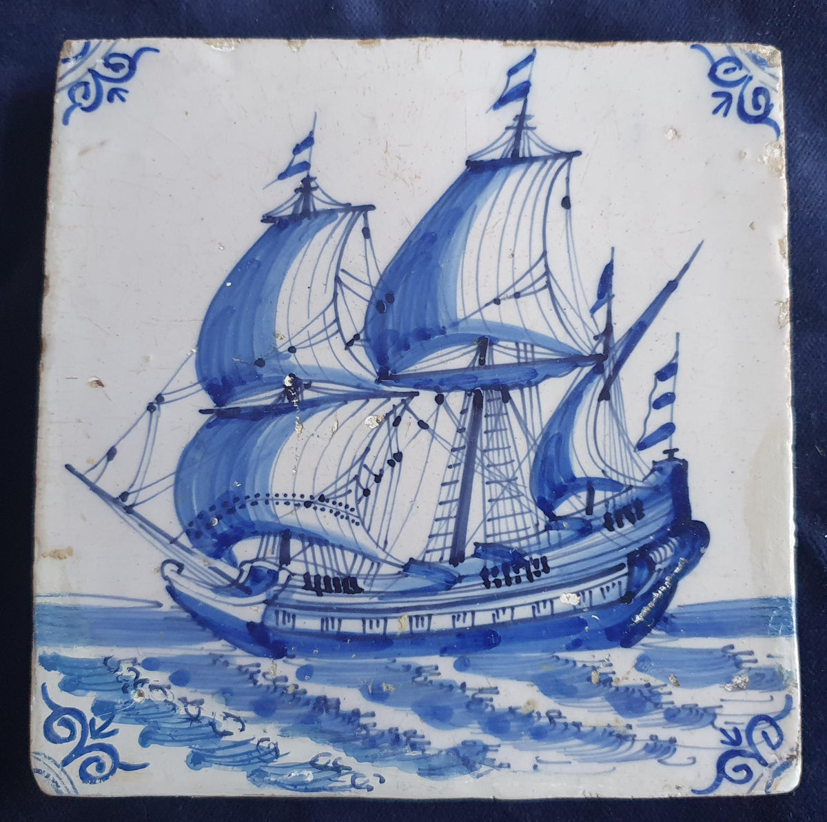 Antique Delft tile dating from around 1650, featuring a beautifully painted depiction of a fully rigged warship at sea. Shiptile