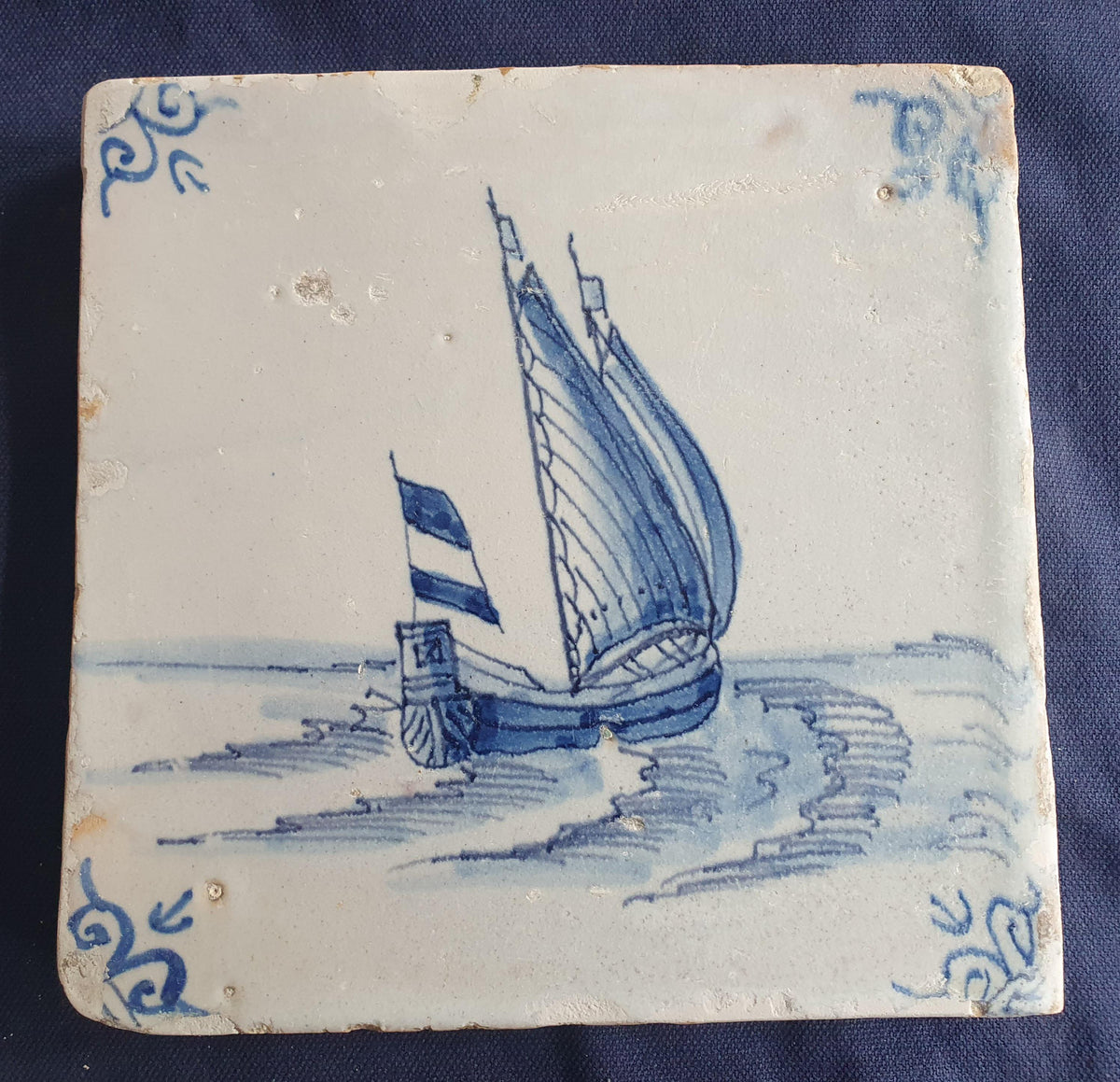 Delft tile, dating from circa 1660, is painted in blue and depicts a ship sailing. Shiptile