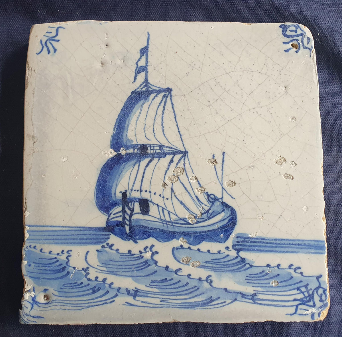 Delft tile, dating from circa 1660, is painted in blue and depicts a ship sailing. Shiptile