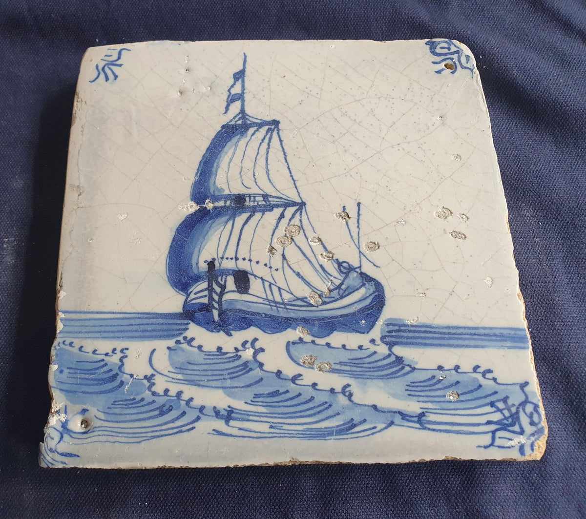 Delft tile, dating from circa 1660, is painted in blue and depicts a ship sailing. Shiptile