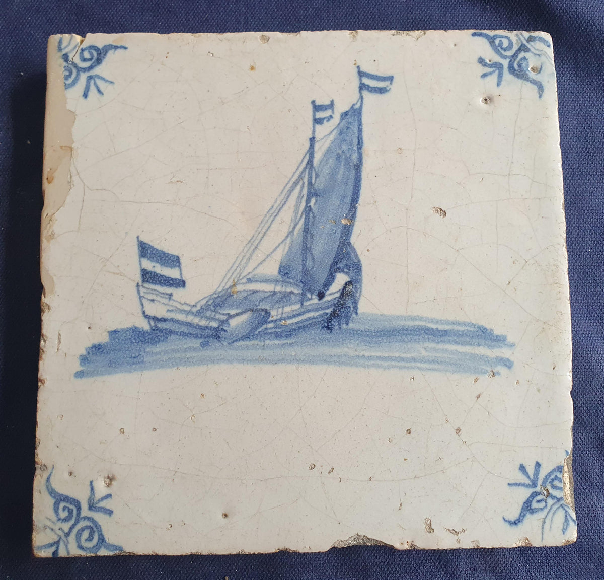 Delft tile, dating from circa 1660, is painted in blue and depicts a ship sailing. Shiptile