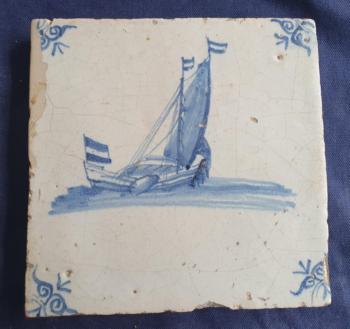 Delft tile, dating from circa 1660, is painted in blue and depicts a ship sailing. Shiptile